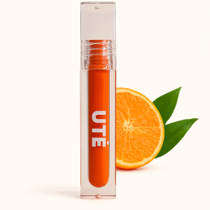 Gloss vegano color mandarina Mandarina Kiss de UTĒ Makeup sobre fondo neutro con detalle natural